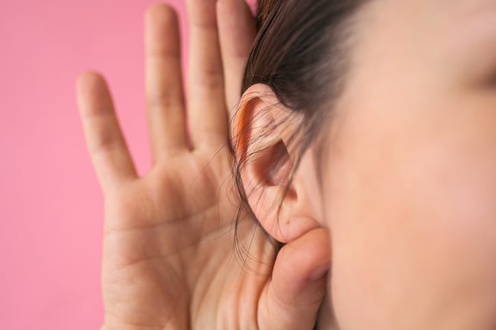 A person cupping a hand around their ear