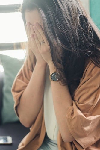 Woman holding hands up to her face.