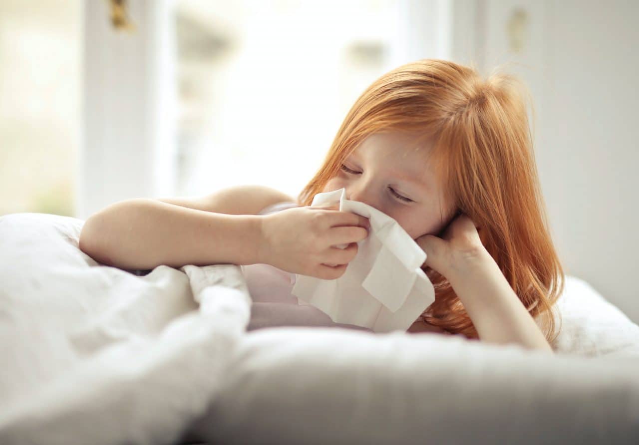 Young girl putting a tissue to her nose.