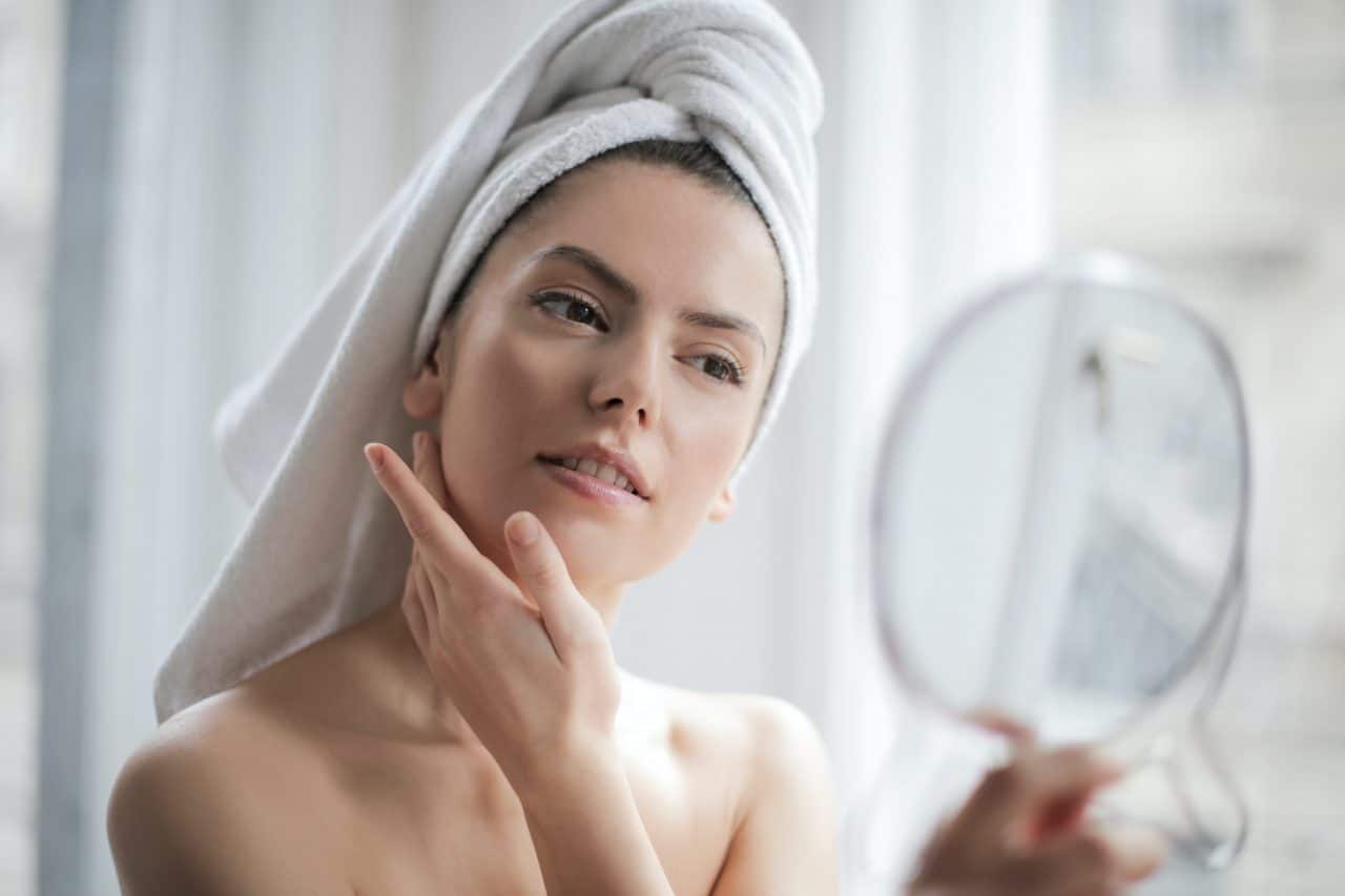 Woman rubbing lotion on her face after a shower.