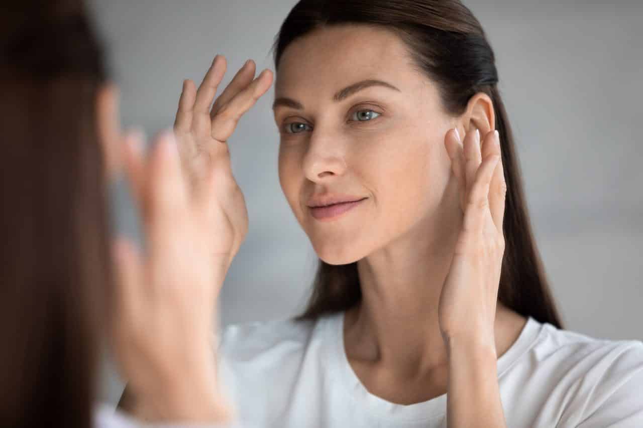 Woman with smooth, clear complexion looking in the mirror.