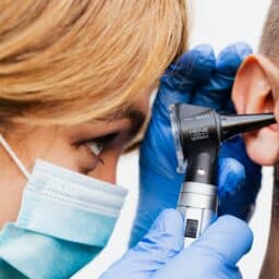 An ENT specialist examining a man's ear.