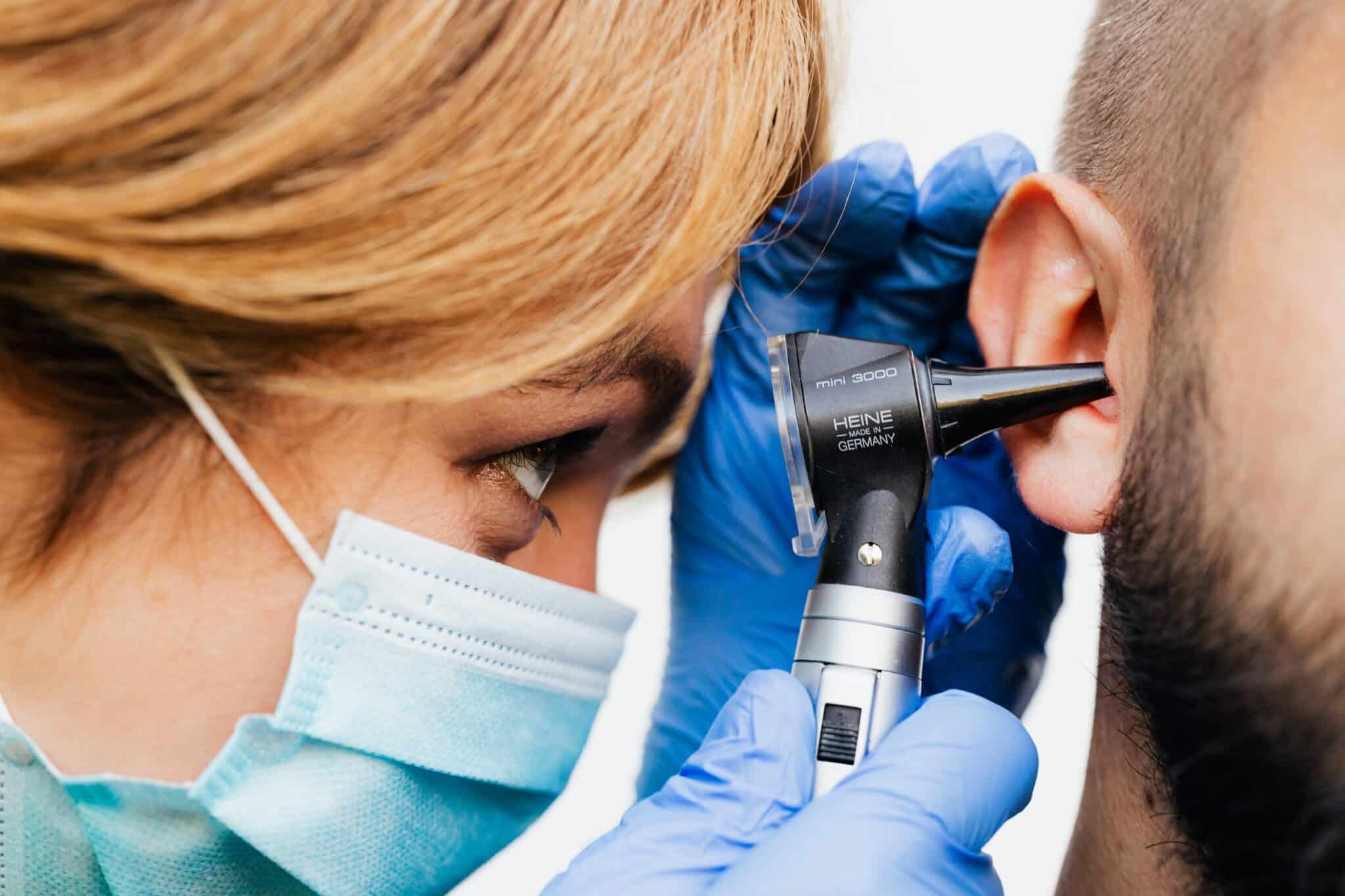 An ENT specialist examining a man's ear.